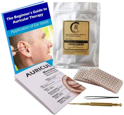 book labelled "guide to auriculotherapy" along with ear map, tweezers, and small black dots (i.e. ear seeds)